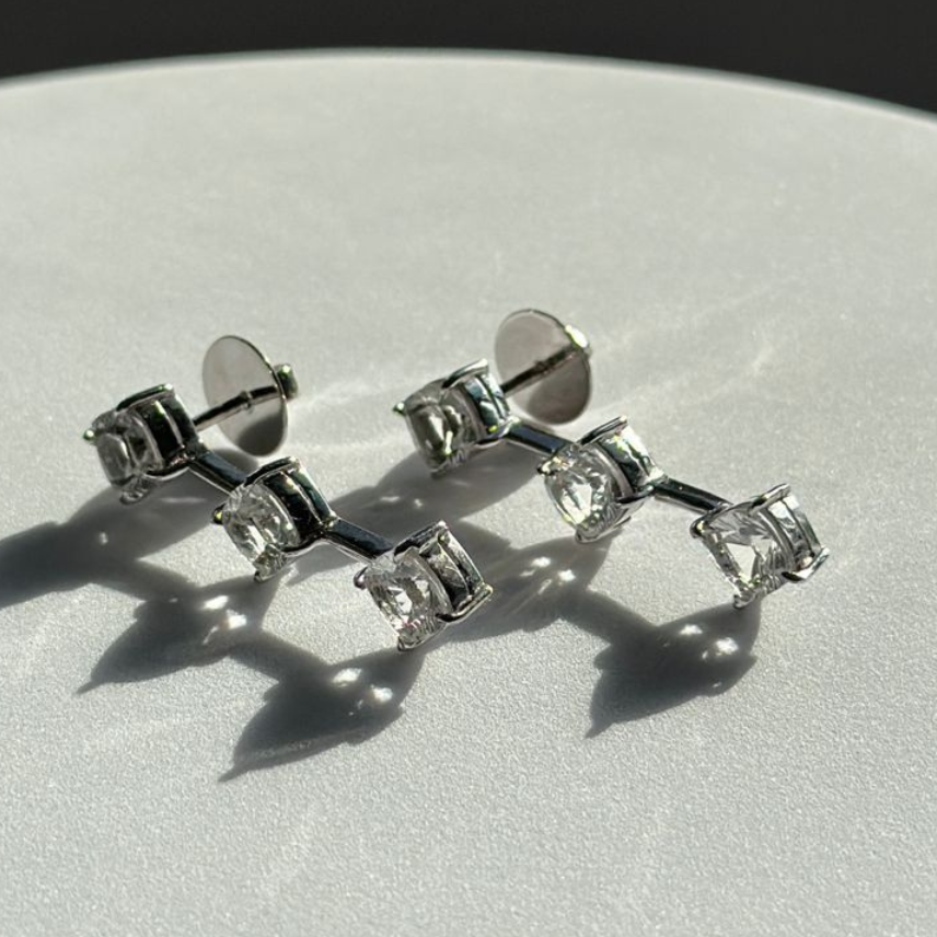 Silver earrings with clear gemstones on a light gray surface